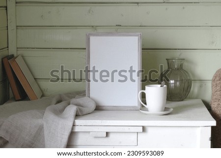 An empty photo frame on the table in the cottage house. Space for editing your text or picture. Mockup, the creator of the scene.