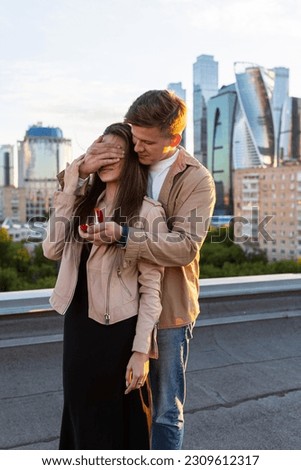 Handsome man is doing surprise marriage proposal to his beautiful girlfriend on a rooftop. Emotional. Happy loving couple on a romantic date on Saint Valentine's Day. Urban cityscape SSTKHome