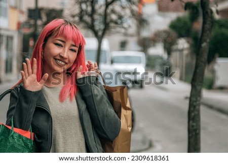 urban woman shopping with bags down the street and waving