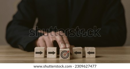 Business strategy. Businessman pointing wooden cube with target board icon and arrow on wooden desk. Goals and planning for success in marketing business, achieve the objective concept. free space..