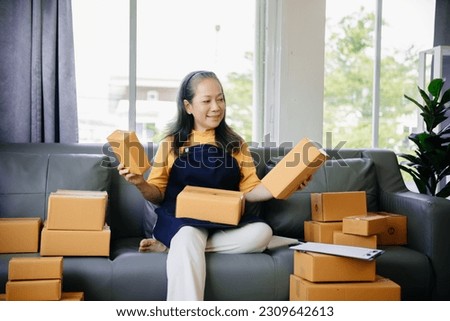 Mature business owner woman prepare parcel box and standing check online orders for deliver to customer on tablet, laptop Shopping Online concept.