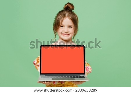 Little child kid girl 6-7 years old wear casual clothes have fun hold use blank screen workspace area laptop pc computer isolated on plain green background. Mother's Day love family lifestyle concept