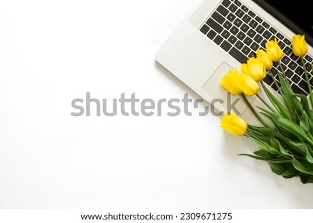 Bouquet of yellow tulips and a laptop on a white background isolated, top view.