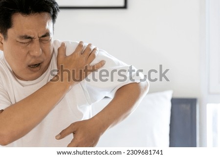 Stressed asian middle aged man suffering from shoulder pain,shoulder dislocation,aching numbness and weakness,tired male patient with Dislocated shoulder joint,discomfort caused by illness or injury Royalty-Free Stock Photo #2309681741