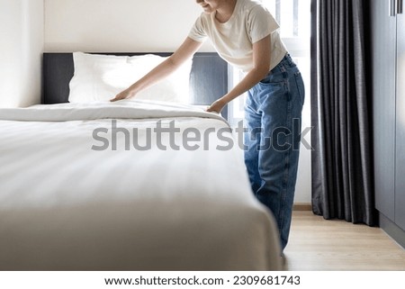 Asian young woman making bed arranging blanket,bedding in her bedroom after wake up,happy smiling teen girl cleaning the room,enjoy while doing housekeeping at home,housework,health hygiene  concept Royalty-Free Stock Photo #2309681743