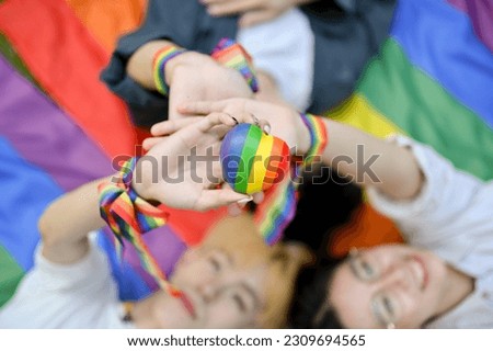 Top view of diverse LGBT friends laying on a pride flag and holding the LGBT heart symbol together. Diversity, Freedom, Equality, LGBTQ