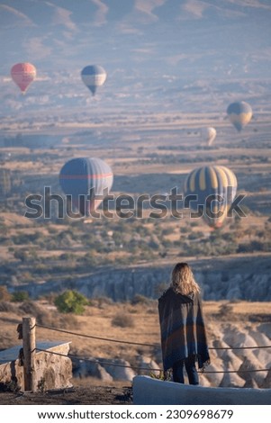Person enjoying the views of hot air balloons flying over Cappadocia in the morning, Turkey