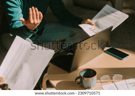 Close up shot of businessman gesticulating with his right hand while explaining something to his colleagues. He is holding documents in the left hand