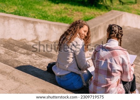 Photo of high school friends sitting on stone steps, enjoying sunny day and having a conversation