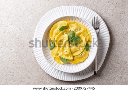 Mezzelune also known as Schlutzkrapfen in Tyrol, and German- crafuncins,  are a semi-circular stuffed pasta, similar to ravioli or pierogi. With popato and goat cheese filling and mint. Royalty-Free Stock Photo #2309727445
