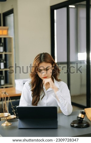 Asian lawyer woman working with a laptop and tablet in a law office. Legal and legal service concept. Looking at camera
