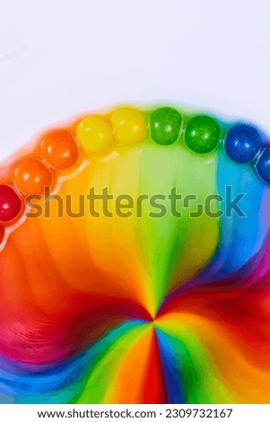 Vertical dome of skittles rainbow candy as sugar and water mix into a psychedelic hippie flower on a white background asset