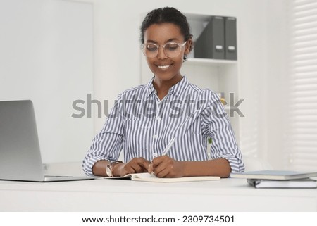 Smiling African American intern working at white table in office