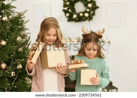 Cute little girls opening Christmas gifts at home