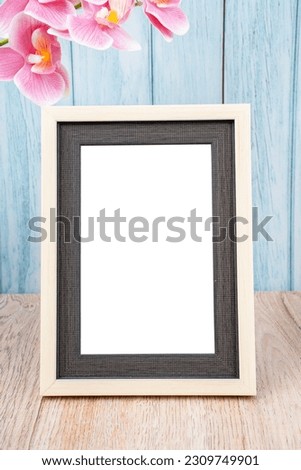 Blank picture frame and pink orchid on blue wall with copy space and clipping path for the inside.