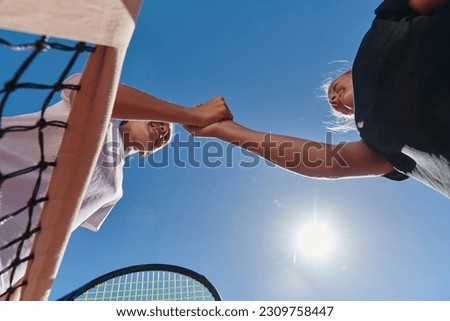 Two female tennis players shaking hands with smiles on a sunny day, exuding sportsmanship and friendship after a competitive match. Royalty-Free Stock Photo #2309758447