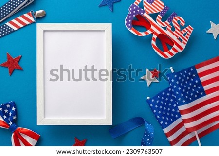 Feel patriotic vibes! Top view of dazzling array of party supplies: suspenders, glittering stars, party eyeglasses, bow-tie, flags on blue background with empty photo frame for picture or promotions