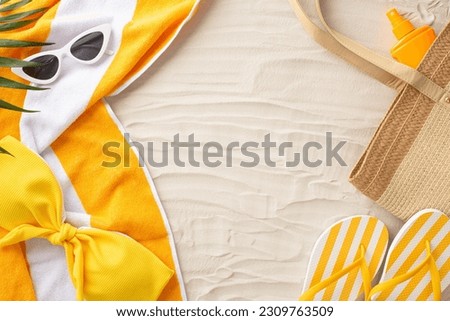 Tropical vibes concept. Top view of summer essentials: sunglasses, beach bag, flip-flops, bikini, sunscreen, towel, palm leaves. Empty space for text or advertisement on sandy beach backdrop Royalty-Free Stock Photo #2309763509
