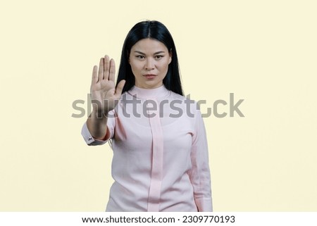 Young asian woman is showing stop gesture by her hand. Palm saying no to you. Isolated on white.