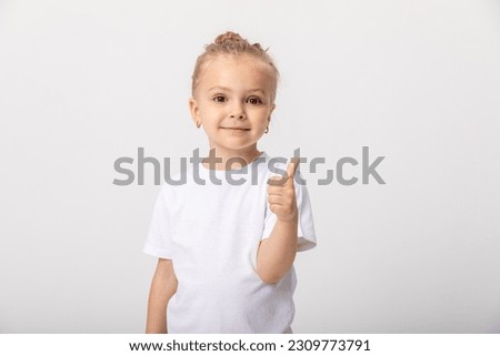 Photo of cheerful happy young small girl make finger thumbs up smile recommend isolated on white background. Space for text. Mock up