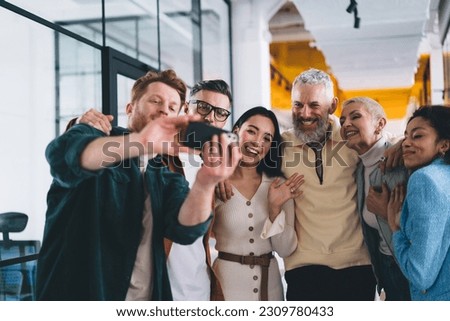 Group of happy male and female colleagues making photos after friendly teamwork brainstorming in office interior, cheerful colleagues enjoying business markieting using cellphone for clicking selfie