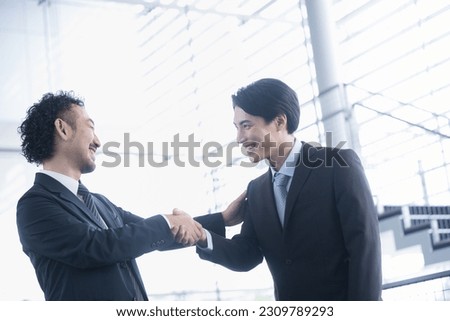 Backlit, shaking hands, contract signing, cooperation, and other images of business success Two Asian men in suits