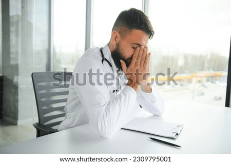 Portrait of exhausted tired young arab male doctor after hard day at work. Royalty-Free Stock Photo #2309795001