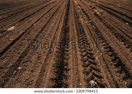 Tractor tyre tracks in plowed field soil in diminishing perspective