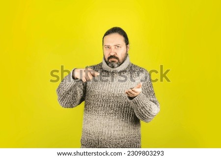 Template with a middle-aged man in a warm sweater with an outstretched hand for editing with a small object. Man on a plain background.