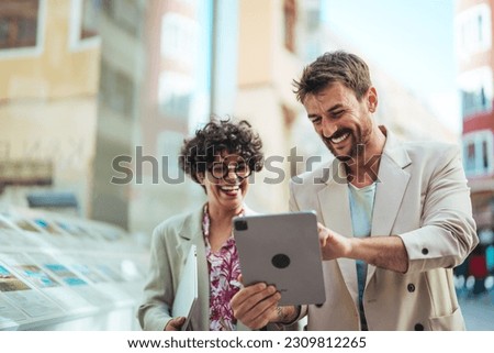 Chasing after success with the best connection. Shot of two businesspeople using a digital tablet in the city. Business colleagues are using digital tablet outside the company building.