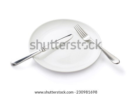 Knife and fork over the empty white ceramic plate isolated over the white background
