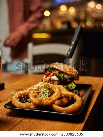 Close-up of young caucasian man in casual clothing with burger and onion rings on table