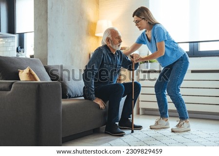 Young caring nurse helping senior old elderly man grandfather walk . Disable old man trying to walk with the assistance aid of female doctor. Treatment and rehabilitation after injury or stroke