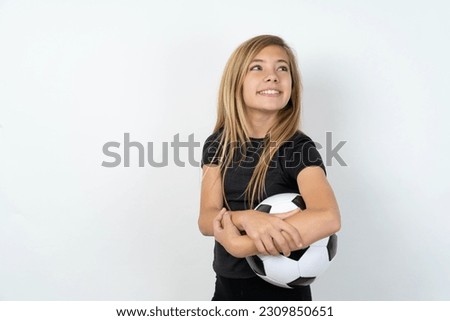 young caucasina girl holding a football ball over white background arms crossed look empty space billboard