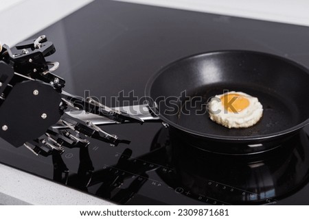 Real robot hand and frying pan with fried egg. Concepts of AI development and robotic process automation. Royalty-Free Stock Photo #2309871681