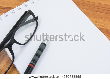Notebook, pen and glasses on wooden table