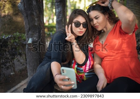 Embrace each other and laughing. Friends making selfie. Two beautiful latin young women making selfie