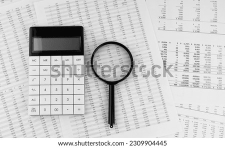 Calculator and magnifying glass on financial statement. Financial, accounting and business concept.