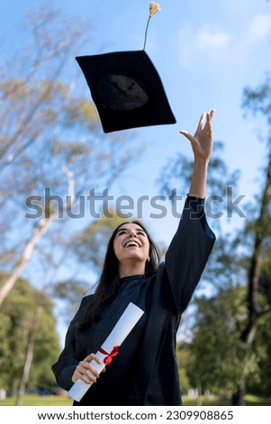 Happy caucasian graduated girl in a black gown throwing the mortarboard to the sky Royalty-Free Stock Photo #2309908865