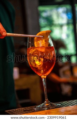 Realistic photo, close-up view of professional bartender in bar making cocktail in a tall glass, with ice and alcohol, male hands in picture