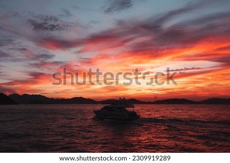 Dramatic and amazing sunset over the sea and skyline, with a boat sailing in the middle