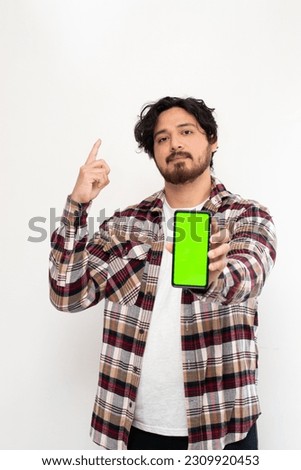 Vertical view of young arabian man holding cell phone with green screen in white background