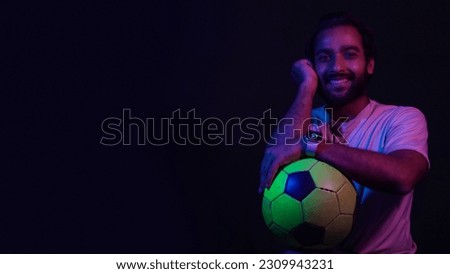 a indian boy with football on black background with light color reflection