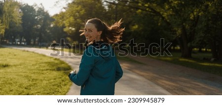 Portrait of smilling young woman running in the city park in the early morning. Royalty-Free Stock Photo #2309945879