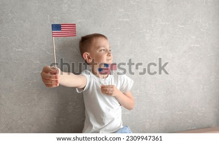 USA Independence Day. Joyful boy holding mini flags of America in his hands