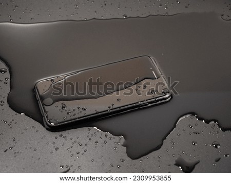 Water has been spilled on the Smartphone. The smartphone fell into the water. Wet smartphone on a black background. Royalty-Free Stock Photo #2309953855