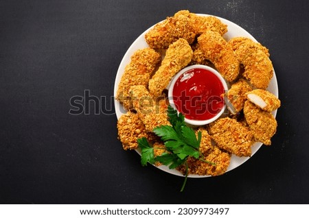 Delicious Crispy Fried Breaded Chicken Breast Strips with Ketchup on Dark Background, Chicken Fingers Royalty-Free Stock Photo #2309973497
