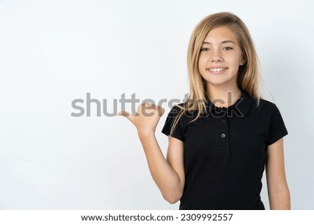 Lovely young caucasian girl wearing black T-shirt over white background pointing aside with forefinger, showing at copy space having news about bargains