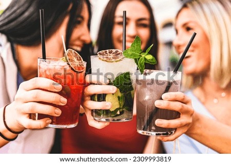 Group of happy friends toasting and drinking fancy cocktails at bar terrace-Three Young girls drink mojito and clinking glass together at pub enjoying happy hour at summer party- Life Style concept Royalty-Free Stock Photo #2309993819
