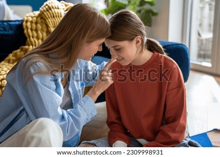 Caring foster mother connects with teenage daughter while sitting on floor at home. Smiling mother and schoolgirl chatting relaxed gossip about school share secrets. Close happy family relationships.  Royalty-Free Stock Photo #2309998931